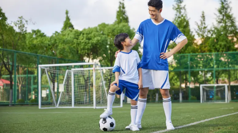 pai e filho se olhando jogando futebol